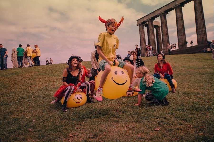 A group of children play on yellow space hoppers.