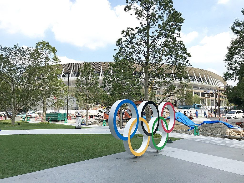 Olympic rings in front of a partially built Olympic stadium in Tokyo, Japan. Built by Kengo Kuma.