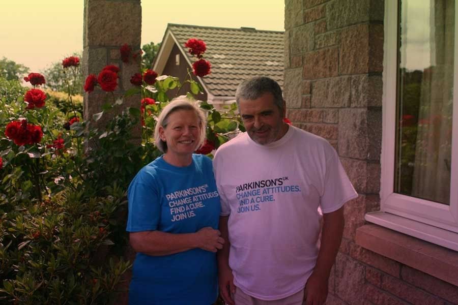 A man and a woman standing next to each other, wearing Parkinsons UK tshirts.