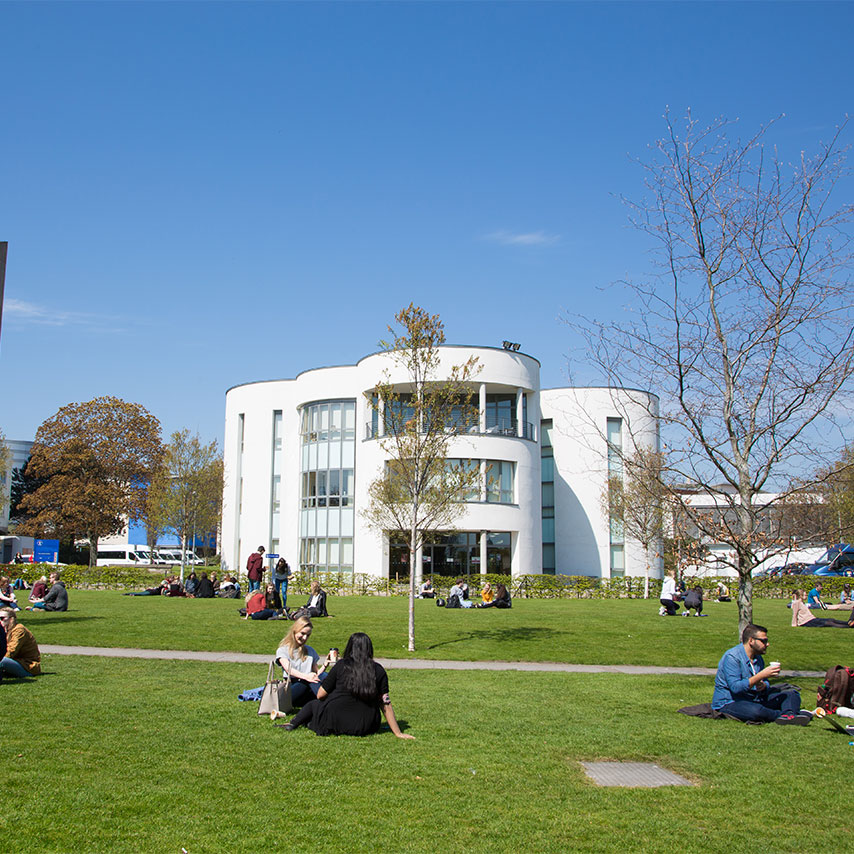 Image of students sitting outside the front of the University of Dundee campus.